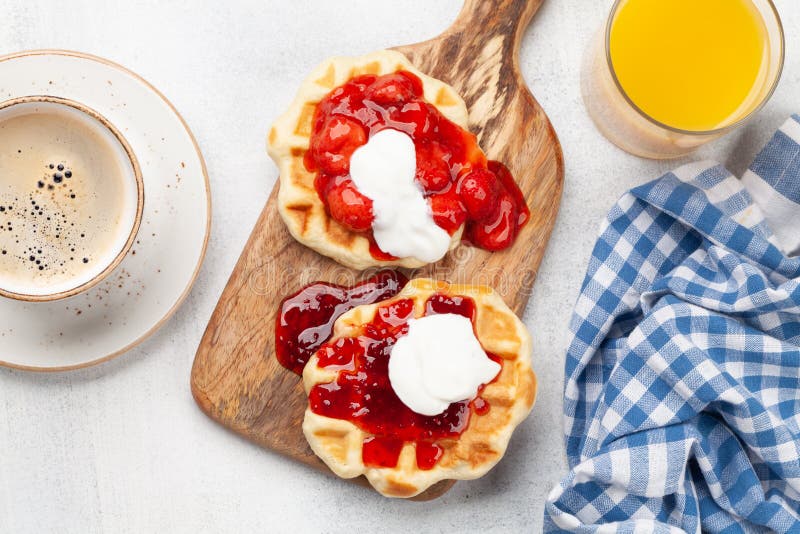 Fresh breakfast waffles with berry jam, coffee and orange