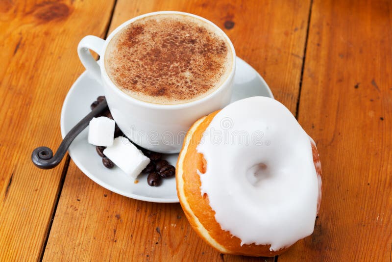 Fresh cappuccino and doughnut with white frosting