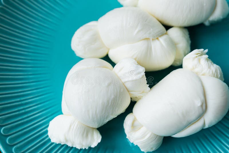 Fresh cheese balls, arranged on a teal plate, exude creamy texture and delicate appeal royalty free stock photo.