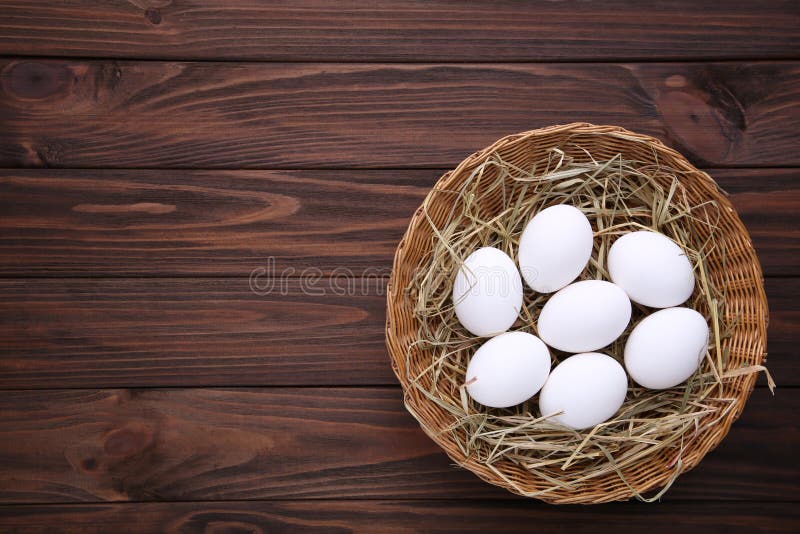 Fresh Chicken Eggs in Basket on Brown Wooden Background Stock Image