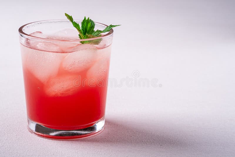 Fresh cold watermelon juice with ice cubes and green mint leaf in glass drink on white background