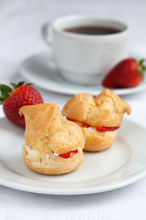 Fresh cream puff with whipped cream and strawberries on white pl