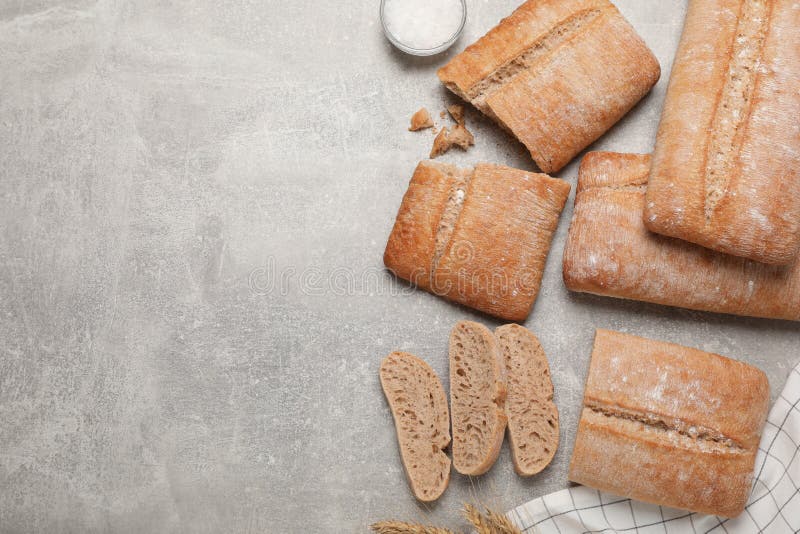 Fresh crispy ciabattas on grey table, flat lay. Space for text