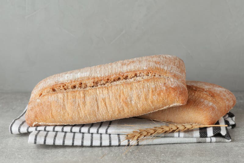 Fresh crispy ciabattas, napkin and spikelet on grey table