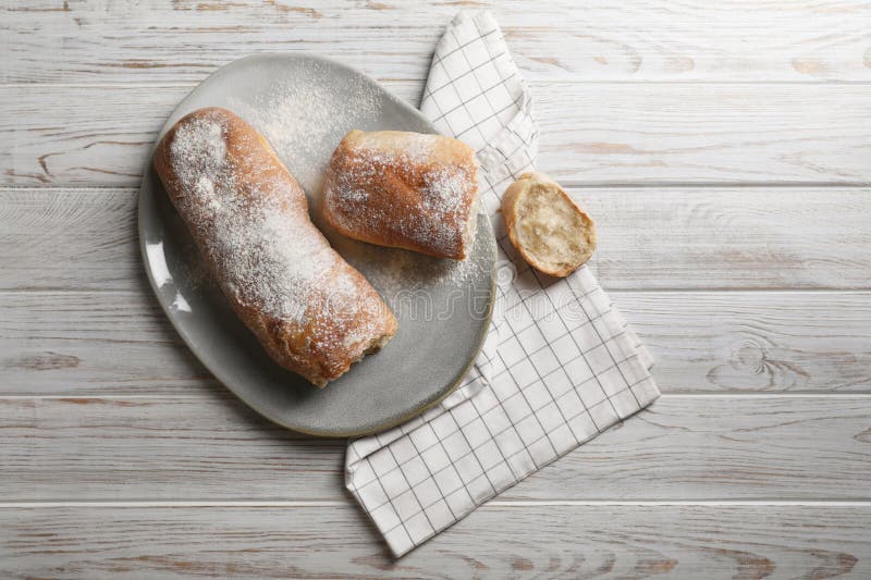 Fresh crispy ciabattas on white wooden table, flat lay. Space for text