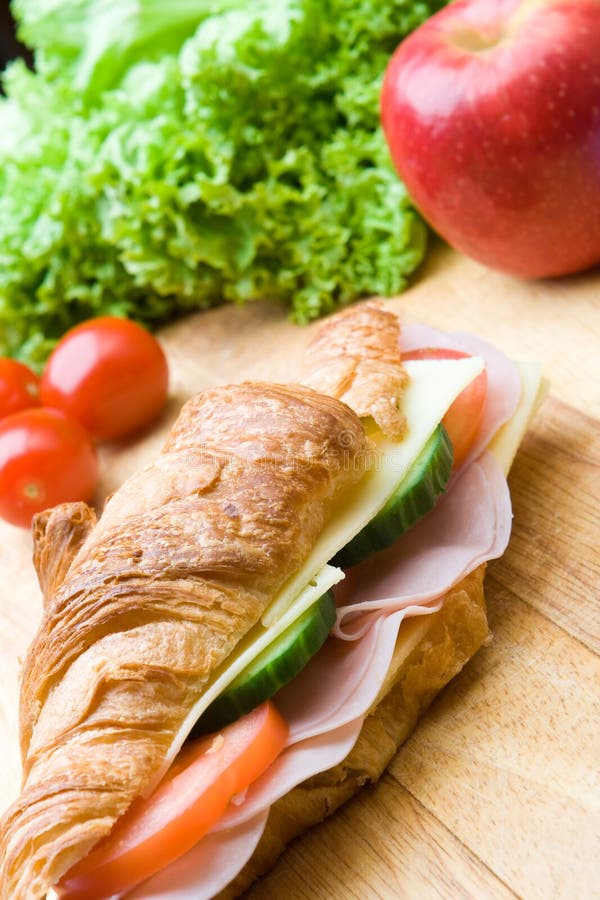 Fresh croissant with ham, cheese and salad