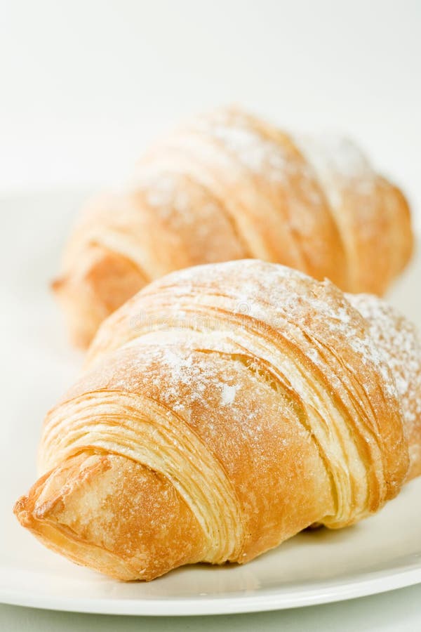 Fresh croissants on white plate with powdered sugar