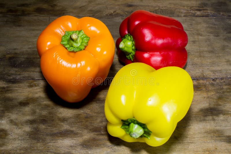 Fresh crop of sweet pepper, red, orange, yellow on a wooden table