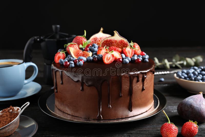 Fresh delicious homemade chocolate cake with berries on table against dark background