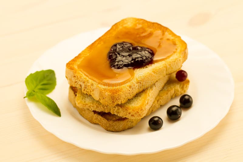 Fresh french toast with honey and jam on a white plate with berries.