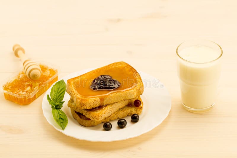 Fresh french toast with honey and jam on a white plate with berries.