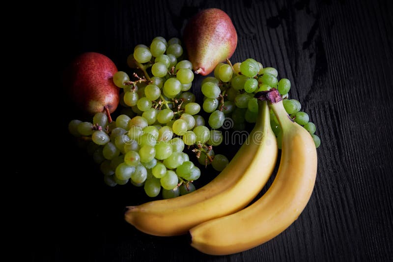 Fresh Fruit On A Dark Background Grapes, Pear And Bananas.Healthy