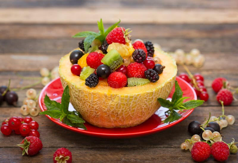 Fresh fruit salad in the melon on the table close up