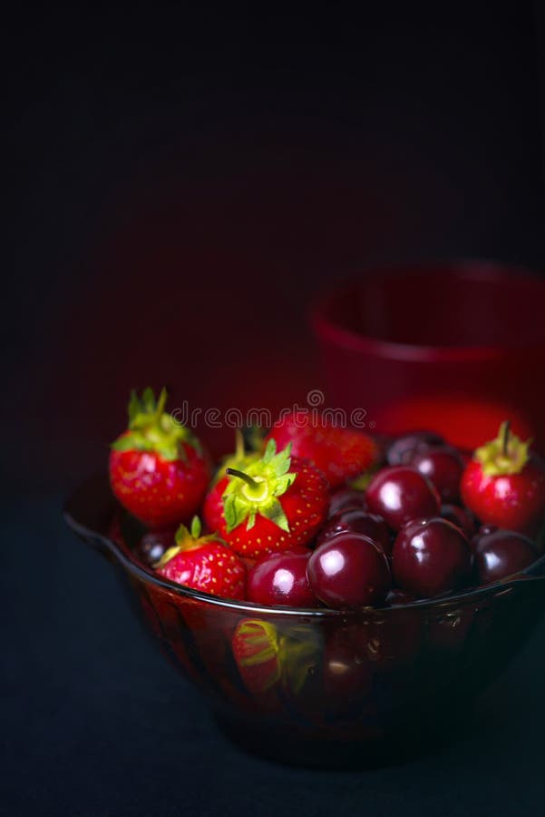 Fresh fruit of strawberries and cherries in a glass dark Cup