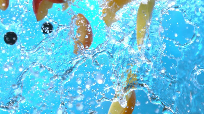 Fresh fruits peach slices orange black currant apple flying into water cascade in slow motion shot at 1500 fps