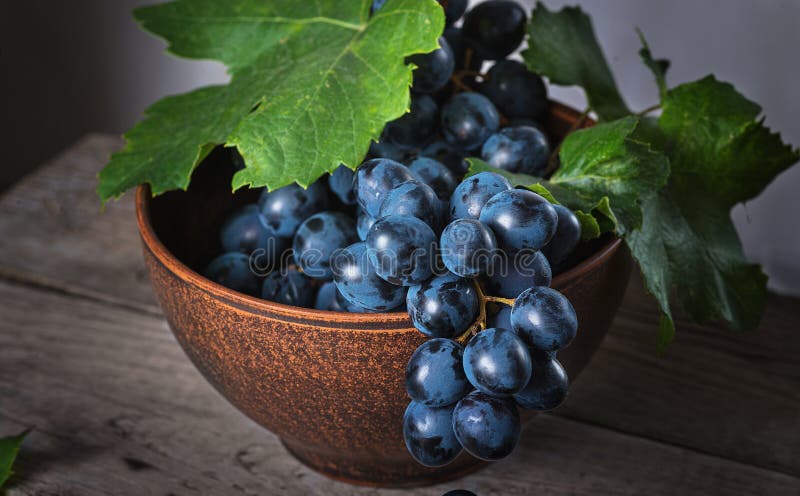 Fresh grapes in a clay plate on a wooden old table