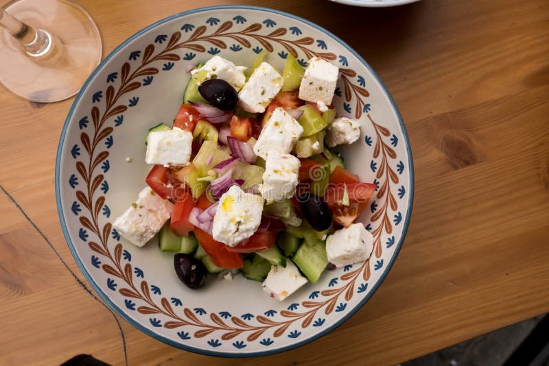 Fresh Greek Salad in pottery bowl on wooden table. Ingredients of Greek Salad including fresh tomatoes, cucumbers, black olives and feta cheese are ready to eat royalty free stock photo Fresh Greek Salad in pottery bowl on wooden table. Ingredients of Greek Salad including fresh tomatoes, cucumbers, black olives and feta cheese are ready to eat royalty free stock photo