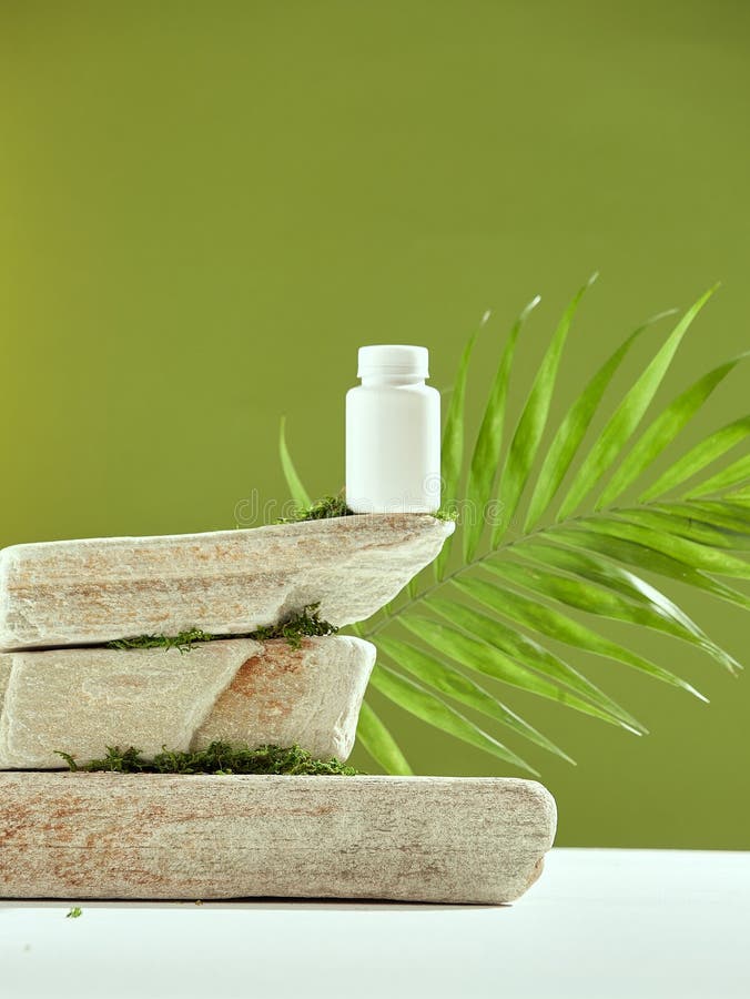 Fresh green scene for natural cosmetic or pharmaceutical product presentation. White plastic mockup jar on podium of stacked stones with palm leaf, moss. Copy space. High quality photo. Fresh green scene for natural cosmetic or pharmaceutical product presentation. White plastic mockup jar on podium of stacked stones with palm leaf, moss. Copy space. High quality photo