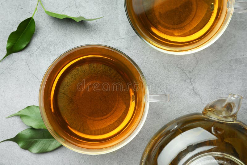 Fresh Green Tea in Glass Cups and Leaves on Grey Table, Flat Lay Stock