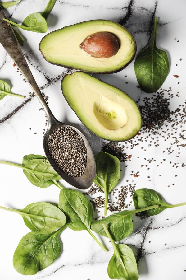 Fresh healthy ingredients for a breakfast on a marble table. Healthy life concept with avocado,chia seeds and spinach