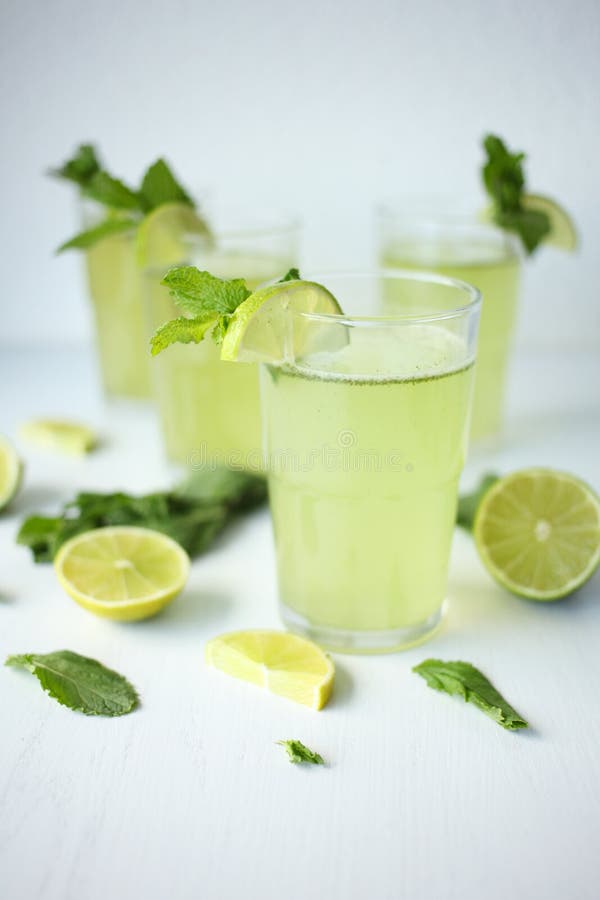 Fresh home-made lemonade with lemon, lime and mint in a glass on white background and ingredients laying on the table royalty free stock photography Fresh home-made lemonade with lemon, lime and mint in a glass on white background and ingredients laying on the table royalty free stock photography