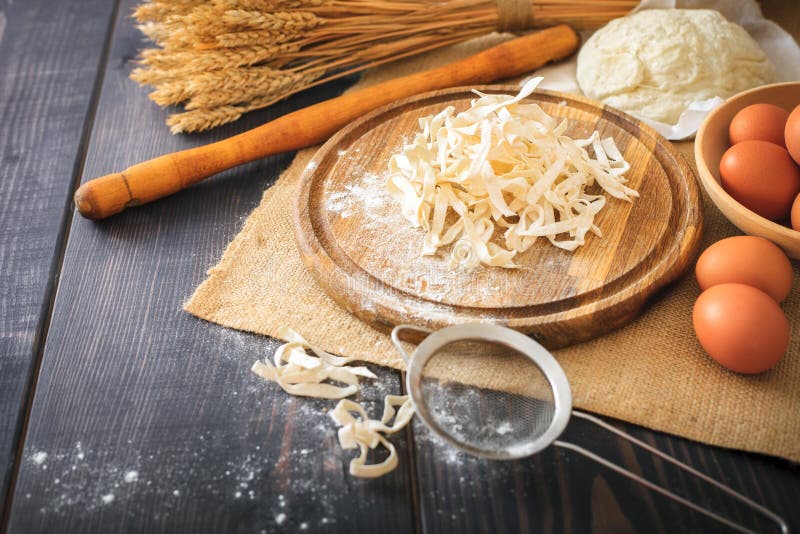 Fresh homemade pasta with pasta ingredients on the wooden table.