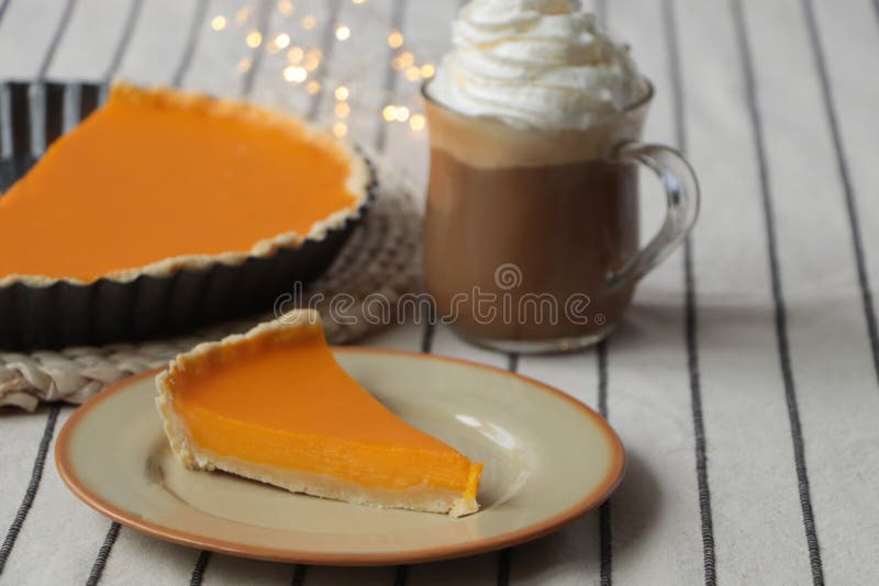 fresh-homemade-pumpkin-pie-and-cup-of-cocoa-with-whipped-cream-on-table