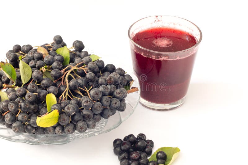 Fresh juice of black chokeberry Aronia melanocarpa in glass and beries in pot, isolated on white background