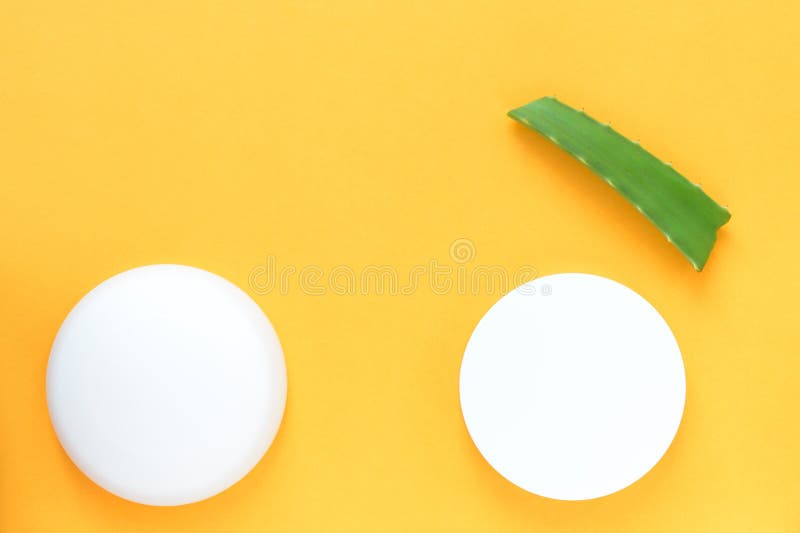Fresh leaf of aloe vera and white jars of cream on a bright yellow background. Organic cosmetics with natural ingredients stock photo Fresh leaf of aloe vera and white jars of cream on a bright yellow background. Organic cosmetics with natural ingredients stock photo