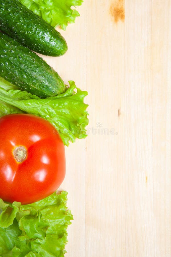 Fresh lettuce salad, tomato and cucumber on wood table