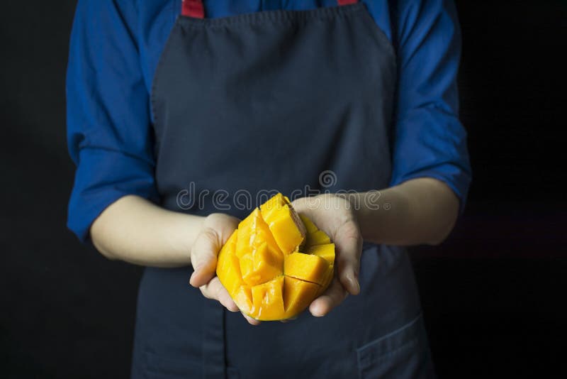 Fresh Mango in the Hands of the Cook. Exotic Fruit. Ripe Mango. Balanced Diet. Dark Background