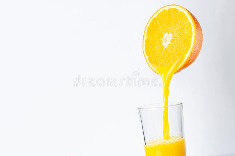 Fresh orange juice is poured from half an orange into a transparent glass. place for inscription
