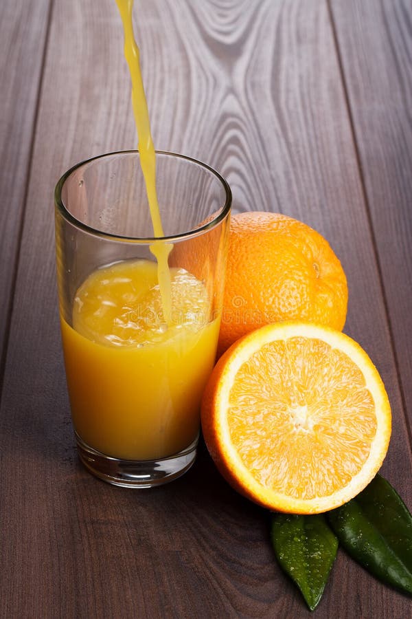 Fresh orange juice pouring into glass on the table