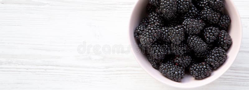 Fresh organic blackberries in pink bowl on a white wooden surface. Close-up. Copy space stock image Fresh organic blackberries in pink bowl on a white wooden surface. Close-up. Copy space stock image
