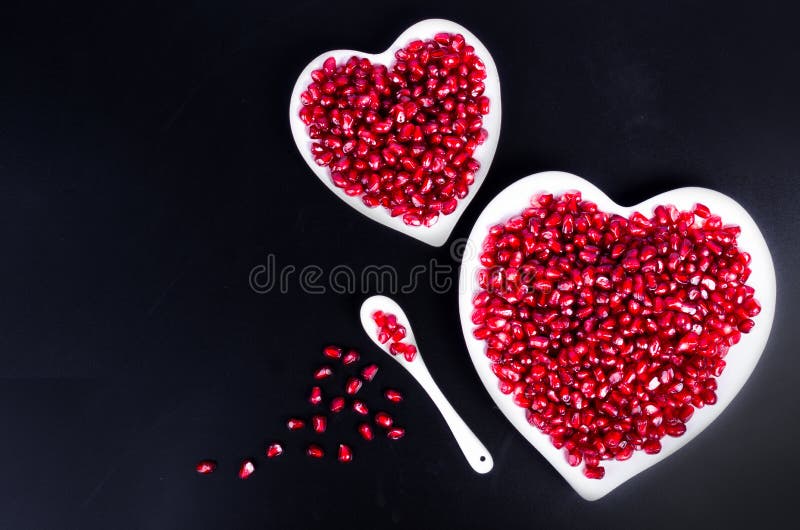 Fresh organic pomegranate seeds in white heart shaped bowl. Free space for your text. royalty free stock photography Fresh organic pomegranate seeds in white heart shaped bowl. Free space for your text. royalty free stock photography