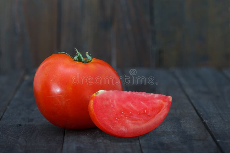 Fresh, organic tomato, one whole and one tomato slice on wooden table stock image Fresh, organic tomato, one whole and one tomato slice on wooden table stock image