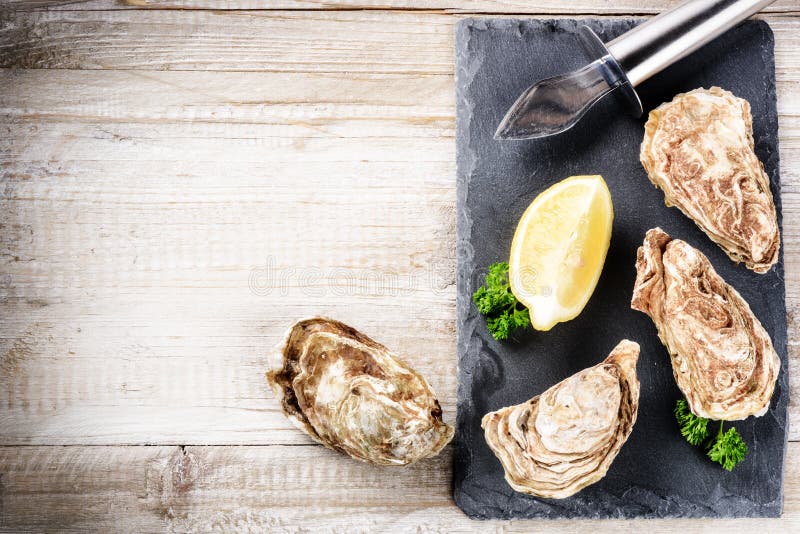 Fresh oysters with lemon on stone plate. Food background royalty free stock photography