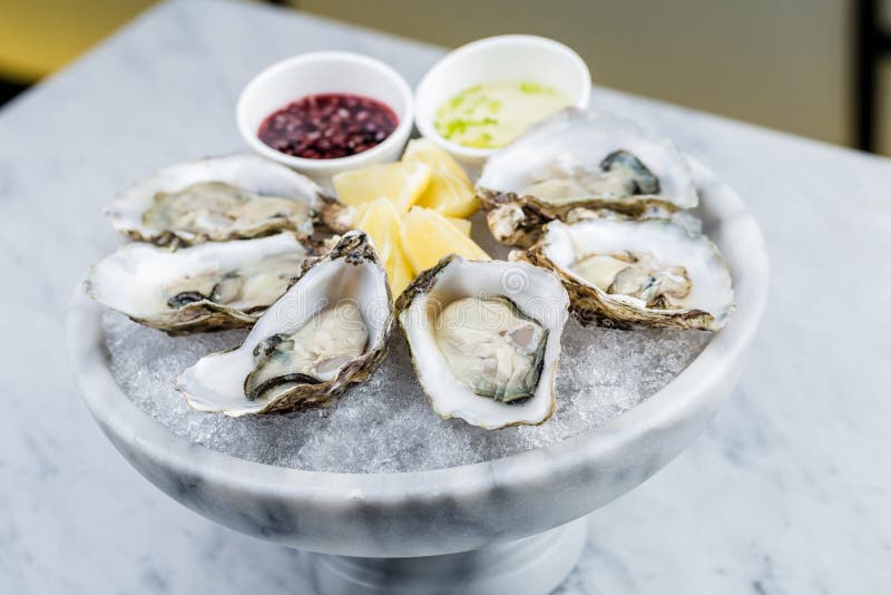 Fresh oysters platter with sauce and lemon royalty free stock photos
