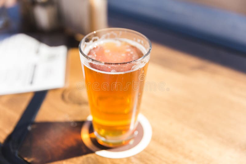 IPA or India Pale Ale beer in a glass on a countertop in sunshine. IPA or India Pale Ale beer in a glass on a countertop in sunshine.