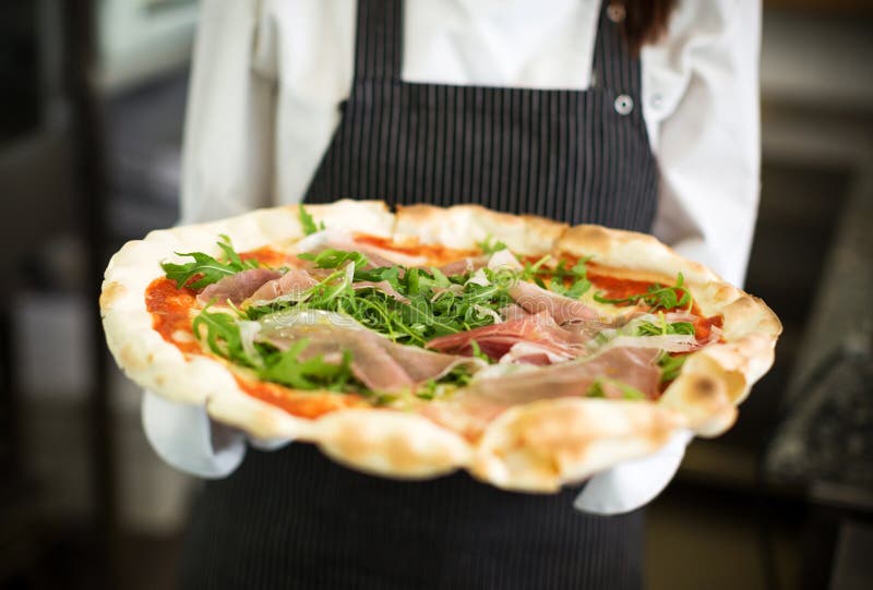 Professional chef in industrial kitchen holding pizza. Professional chef in industrial kitchen holding pizza