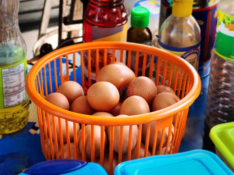 Fresh Raw Chicken Eggs in Orange Plastic Basket in Kitchen Stock Image