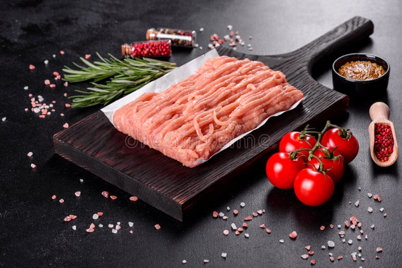 Fresh raw chicken mince on a dark wooden cutting board