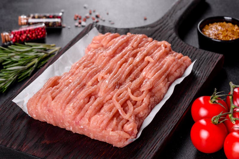 Fresh raw chicken mince on a dark wooden cutting board