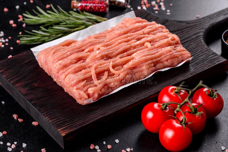 Fresh raw chicken mince on a dark wooden cutting board