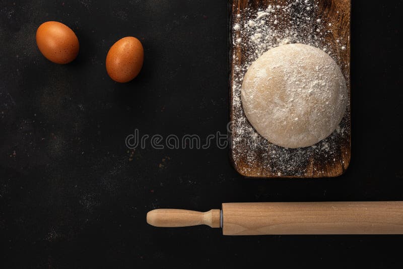 Fresh raw dough for bread or pizza with eggs on a dark background with dusting of flour. Top view. Raw fresh yeast dough stock images, royalty-free photos and pictures