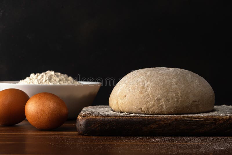 Fresh raw dough for bread or pizza with eggs on a dark wooden table. Raw fresh yeast dough stock images, royalty-free photos and pictures