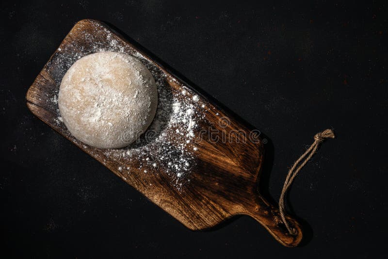 Fresh raw dough for bread or pizza on a rustic wooden background with dusting of flour. Top view. Raw fresh yeast dough stock images, royalty-free photos and pictures