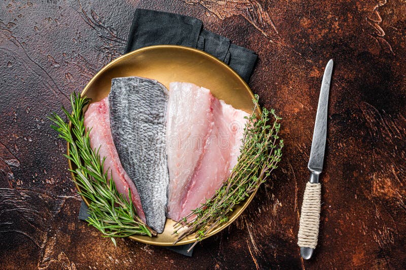 Fresh Raw Gilthead Sea bream fish fillets ready for cooking. Dark background. Top view