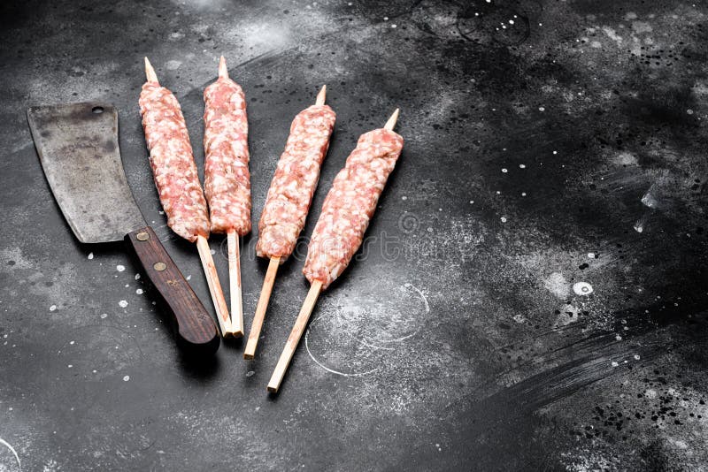 Fresh Raw Kofta or Lula Kebabs Skewers, on Black Dark Stone Table