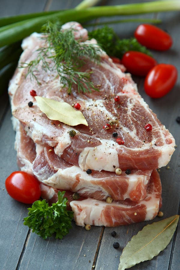 Fresh raw pork shoulder chop with spices and vegetables